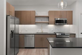 A modern kitchen with a stainless steel refrigerator, microwave, and oven.